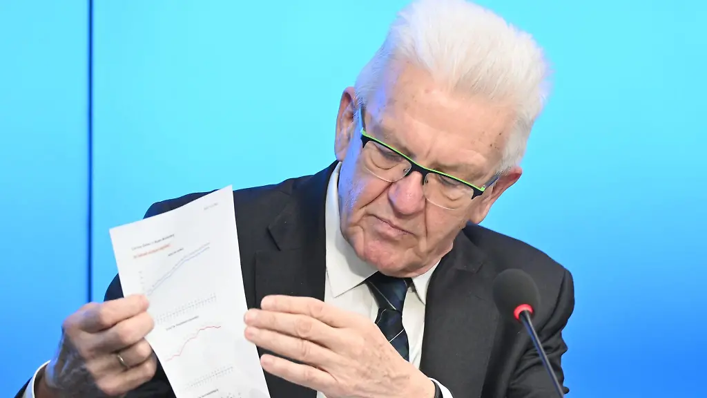 Winfried-Kretschmann-zeigt-ein-Blatt-mit-Corona-Tabellen-auf-der-Regierungspressekonferenz