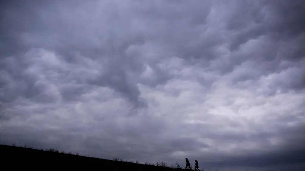Zwei-Frauen-laufen-vor-wolkenverhangenen-Himmel-auf-einen-Huegel-am-Kronsberg