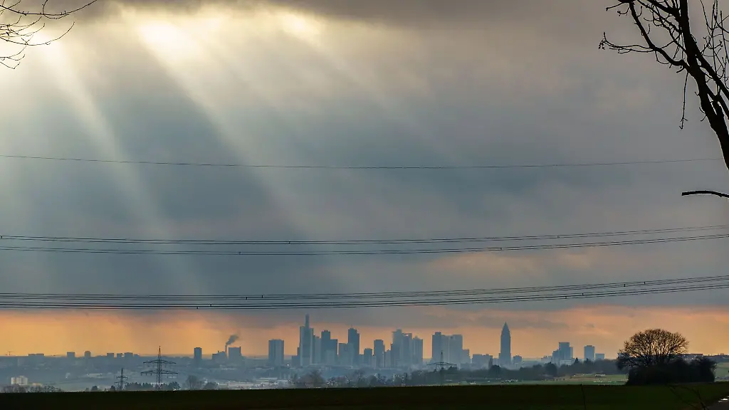 Einzelne-Sonnenstrahlen-brechen-durch-die-Wolkendecke-ueber-der-Frankfurter-Skyline