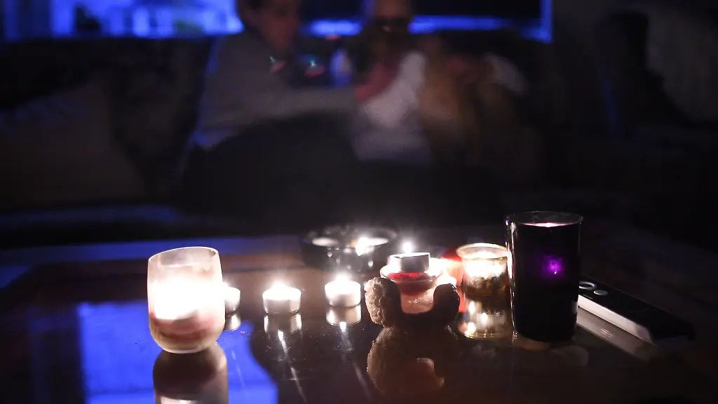 Eine-Mutter-sitzt-bei-Kerzenschein-mit-ihrer-Tochter-und-ihrem-Hund-im-Wohnzimmer