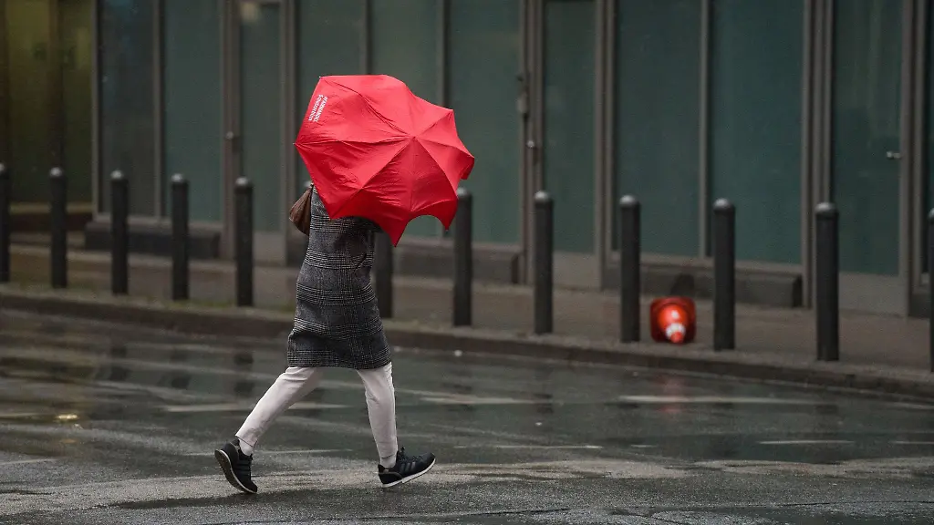 Eine-Frau-ueberquert-bei-Regen-eine-Strasse-in-der-Frankfurter-Innenstadt