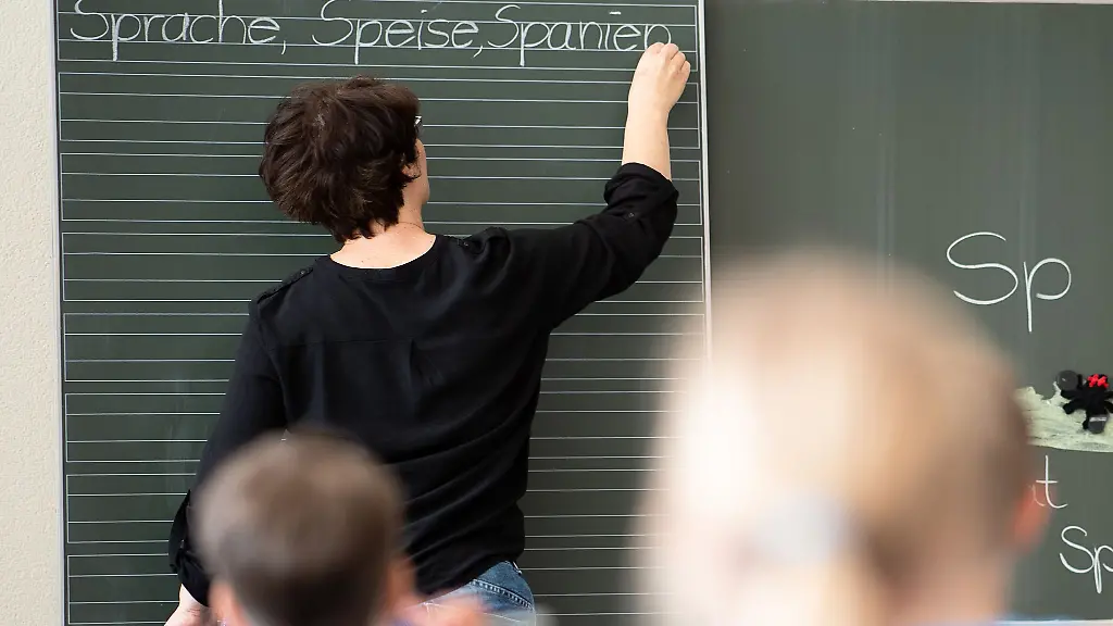 Eine-Lehrerin-schreibt-in-einer-Grundschule-Worte-an-eine-Tafel