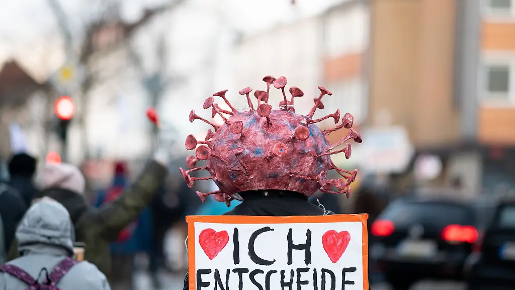 Ein-Teilnehmer-einer-Demonstration-gegen-die-Corona-Massnahmen-traegt-eine-Virus-Kopfbedeckung