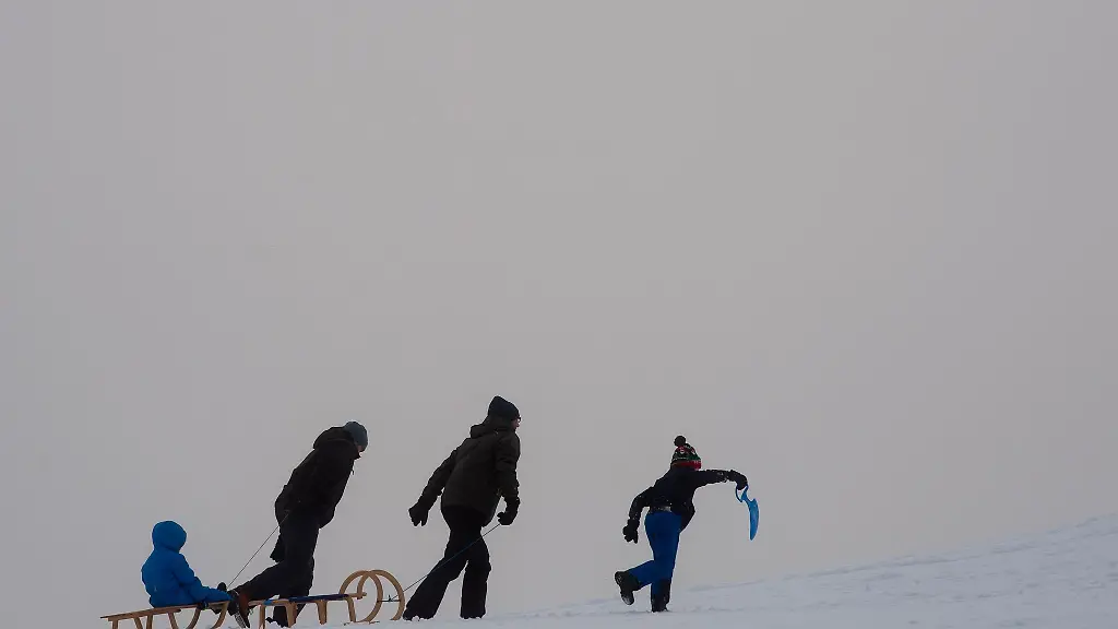 Wintersportler-gehen-einen-Rodelhang-am-Sonnenberg-hinauf