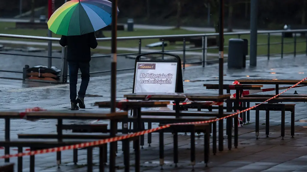 Ein-Passant-geht-unter-einem-bunten-Regenschirm-an-der-Uferprommenade-des-Phoenix-Sees-vorbei