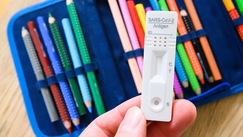 Ein-Corona-Selbsttest-wird-ueber-einem-Federmaeppchen-gehalten