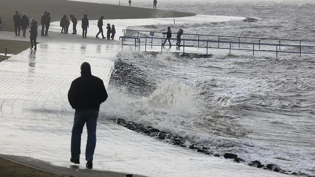 Spaziergaenger-sind-bei-Sturm-an-der-aufgepeitschten-Nordsee-unterwegs
