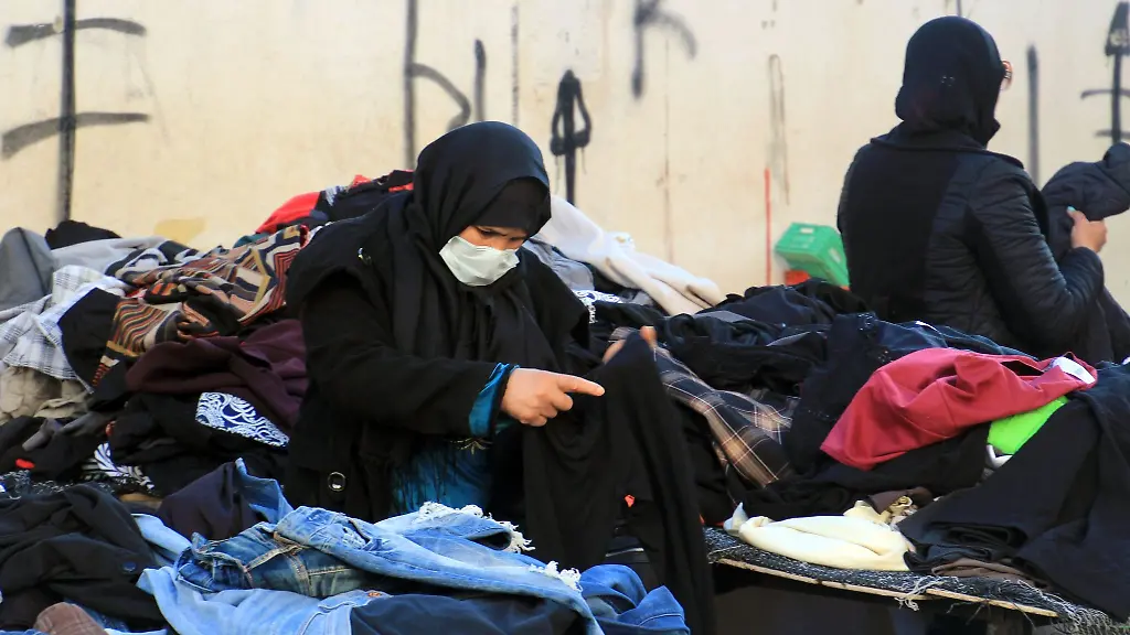 Eine-Kundin-schaut-sich-gebrauchte-Kleidungsstuecke-auf-einem-zentralen-Markt-in-Tunesiens-Hauptstadt-an