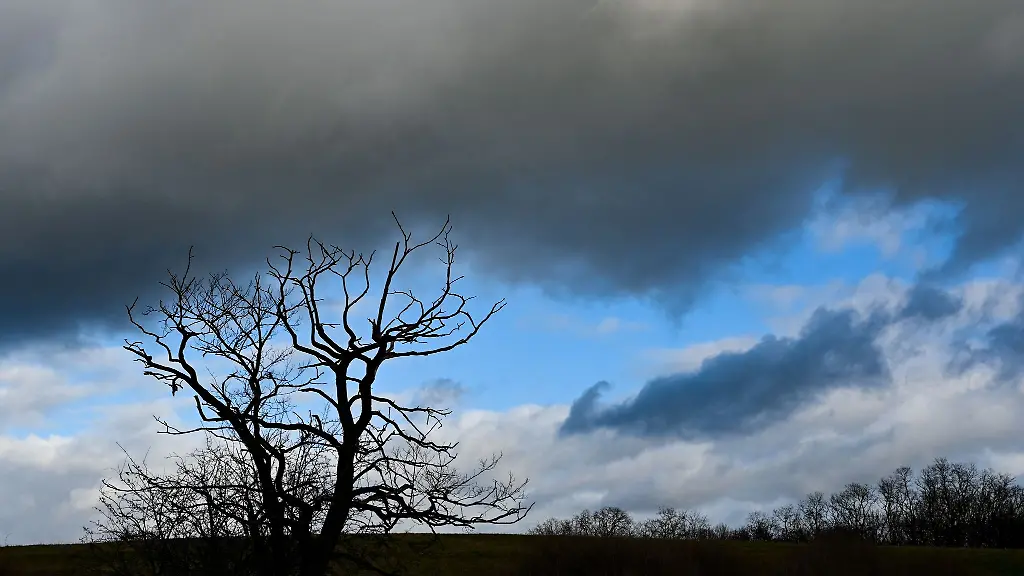 Dunkle-Wolken-ziehen-ueber-eine-Landschaft