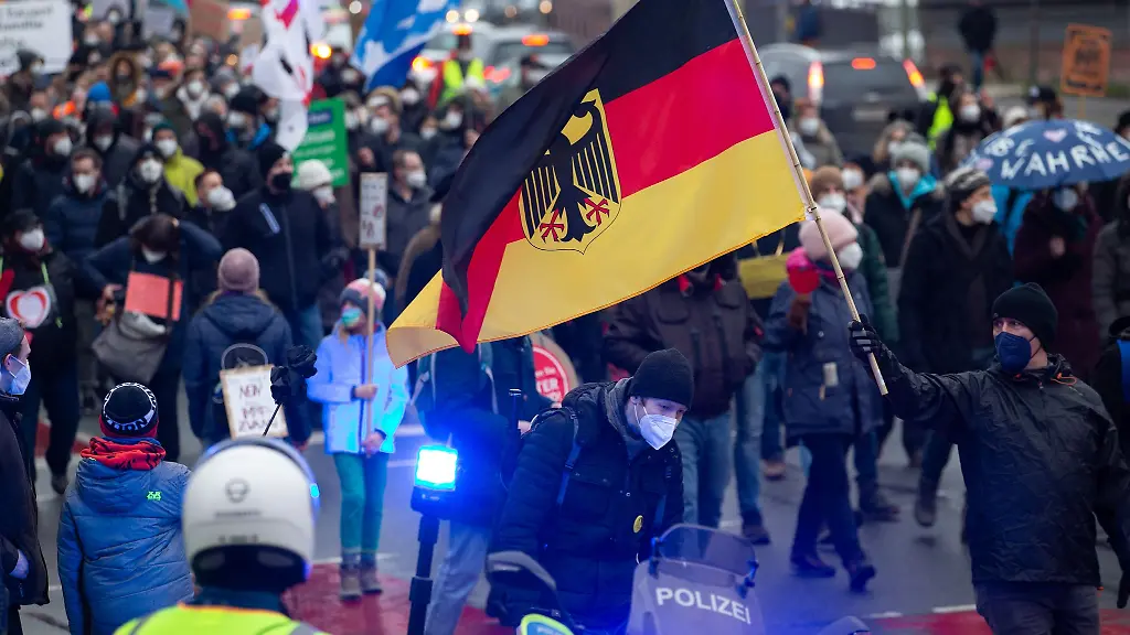 Demonstranten-gehen-mit-einer-Deutschlandflagge-ueber-eine-von-der-Polizei-abgesperrte-Strasse