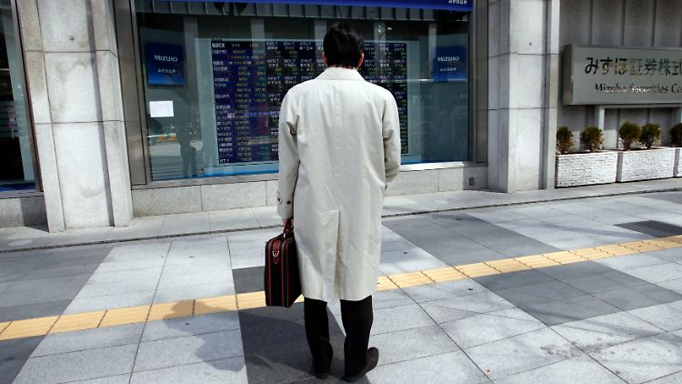 In Tokyo betrachtet ein Passant eine Anzeigetafel mit Börsenkursen.