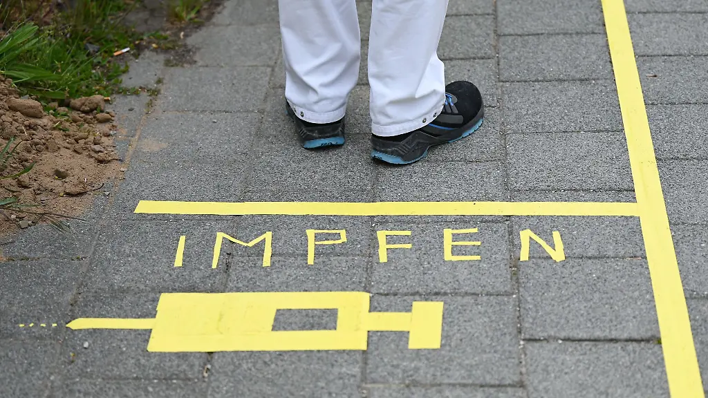 Ein-Mann-steht-an-einem-Covid-19-Impfcenter-hinter-der-Bodenaufschrift-Impfen