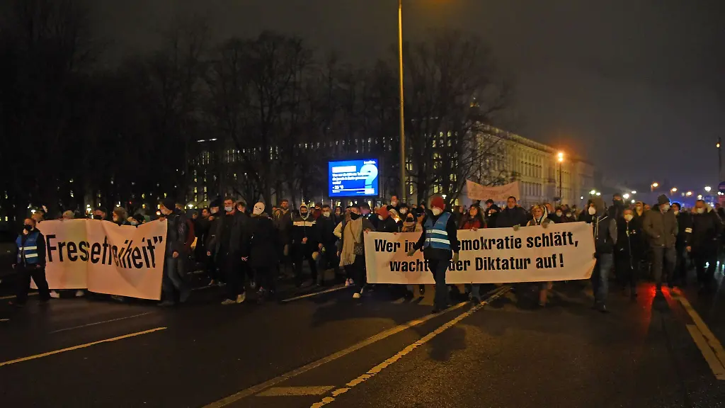 Teilnehmer-einer-Demonstration-gegen-die-Corona-Massnahmen-gehen-mit-Transparenten-durch-die-Stadt