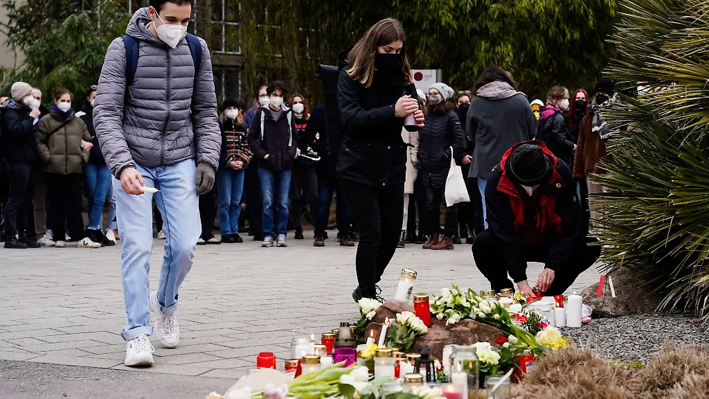 Menschen-legen-vor-einem-Gebaeude-der-Universitaet-Blumen-und-Kerzen-an-den-Wegesrand