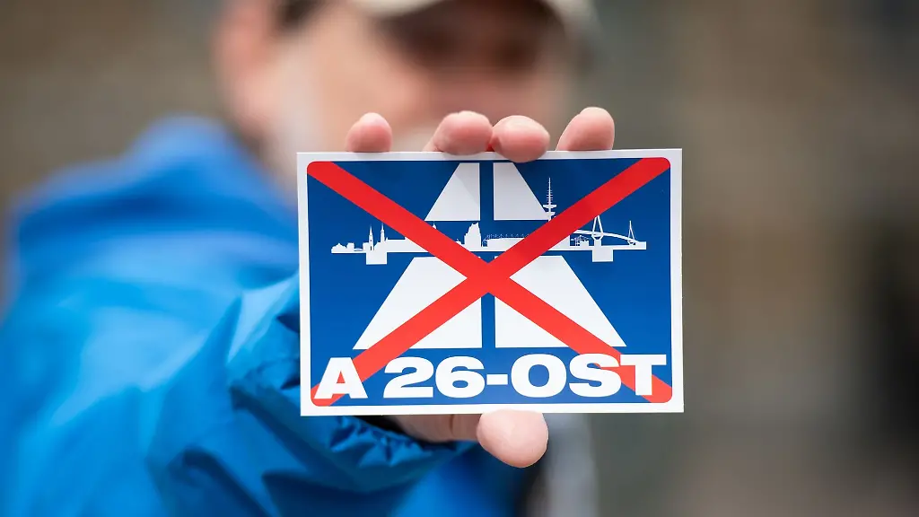 Ein-Nabu-Aktivist-haelt-waehrend-einer-Demo-einen-Aufkleber-mit-dem-durchgestrichenen-Schriftzug-A26-OST-in-der-Hand