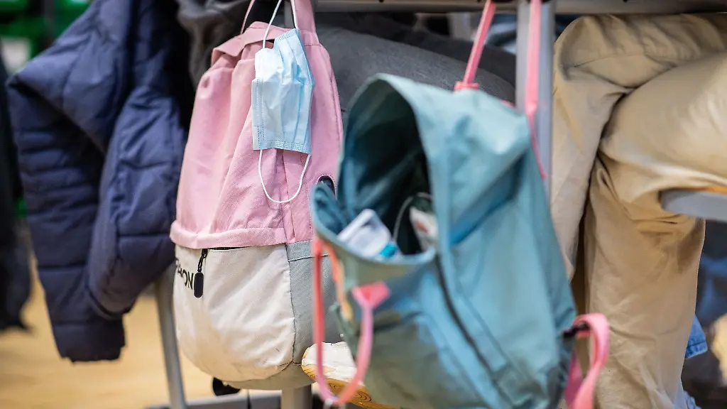 Eine-Maske-haengt-im-Klassenzimmer-am-Rucksack-einer-Schuelerin