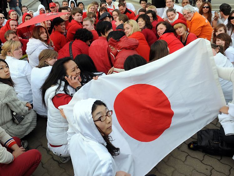 In Berlin bilden Menschen mit ihrer roten und weißen Kleidung die japanische Flagge nach.