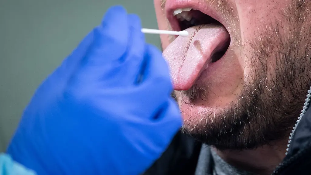 Ein-Mann-fuehrt-in-einem-Covid-19-Testcenter-einen-Rachenabstrich-bei-einem-Mann-durch