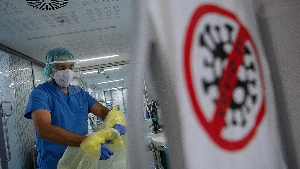 Ein-Pfleger-zieht-beim-Verlassen-der-Intensivstation-fuer-Corona-Patienten-seinen-Schutzkittel-aus