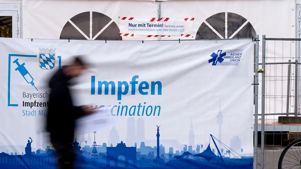 Ein-Mann-geht-auf-der-Theresienwiese-an-einer-Corona-Impfstation-vorbei