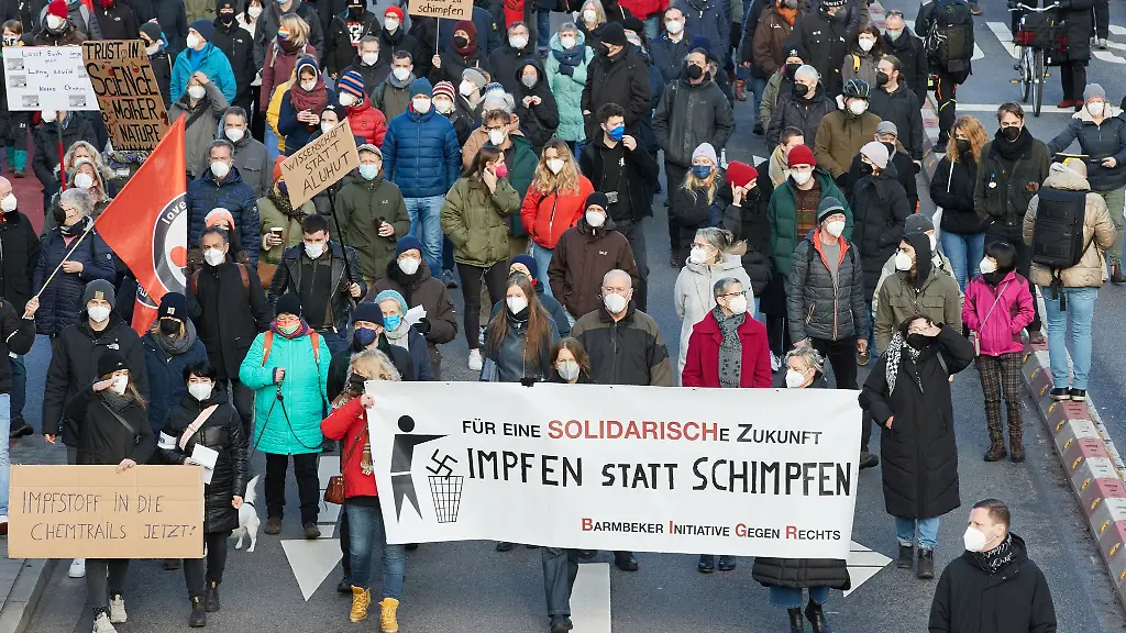 Teilnehmer-einer-Demonstration-unter-dem-Motto-Solidaritaet-und-Aufklaerung-statt-Verschwoerungsideologien-halten-ein-Transparent-mit-der-Aufschrift-Impfen-statt-schimpfen