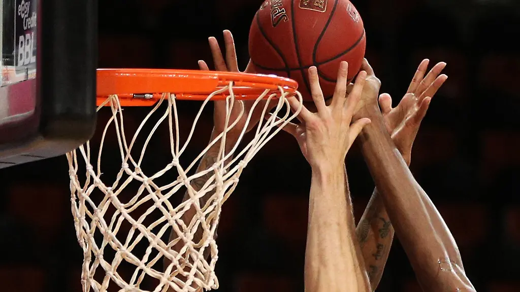 Spieler-zweier-Basketballmannschaften-im-Kampf-um-den-Ball