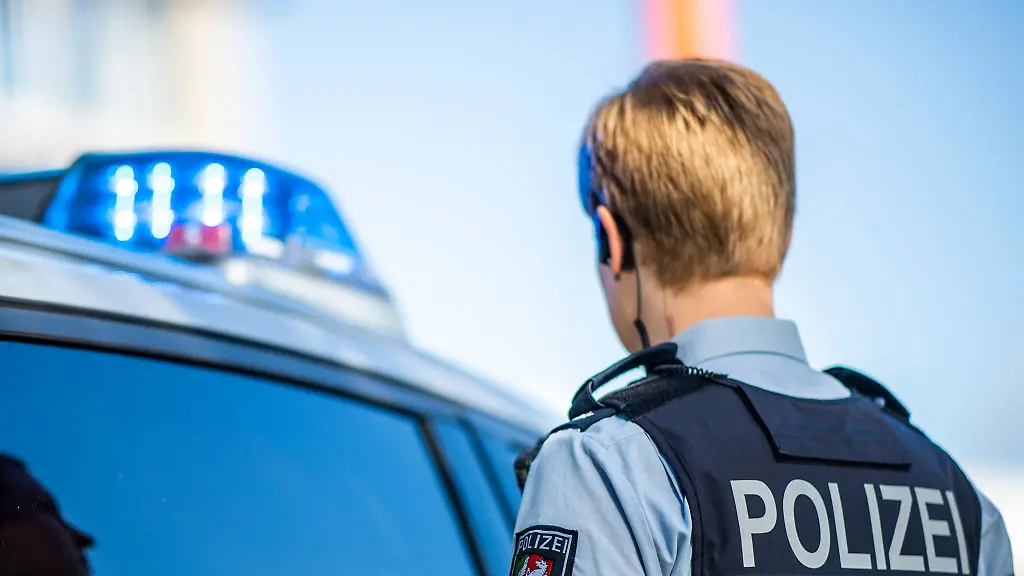 Eine-Polizistin-steht-vor-einem-Streifenwagen