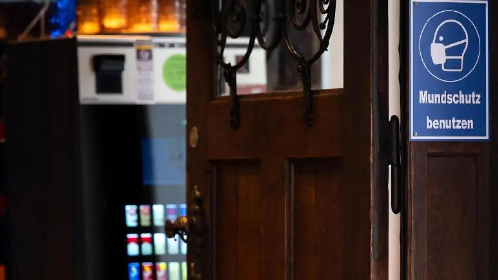 Ein-Schild-mit-der-Aufschrift-Mundschutz-benutzen-ist-am-Eingang-eines-Wirtshauses-zu-sehen