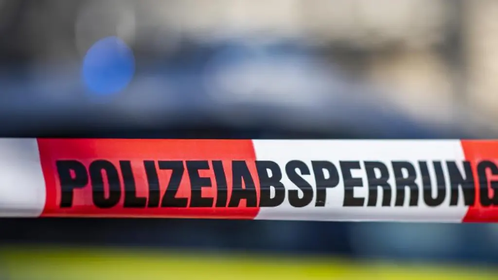 Ein-Absperrband-mit-der-Aufschrift-Polizeiabsperrung-ist-vor-einem-Polizeiwagen-aufgespannt