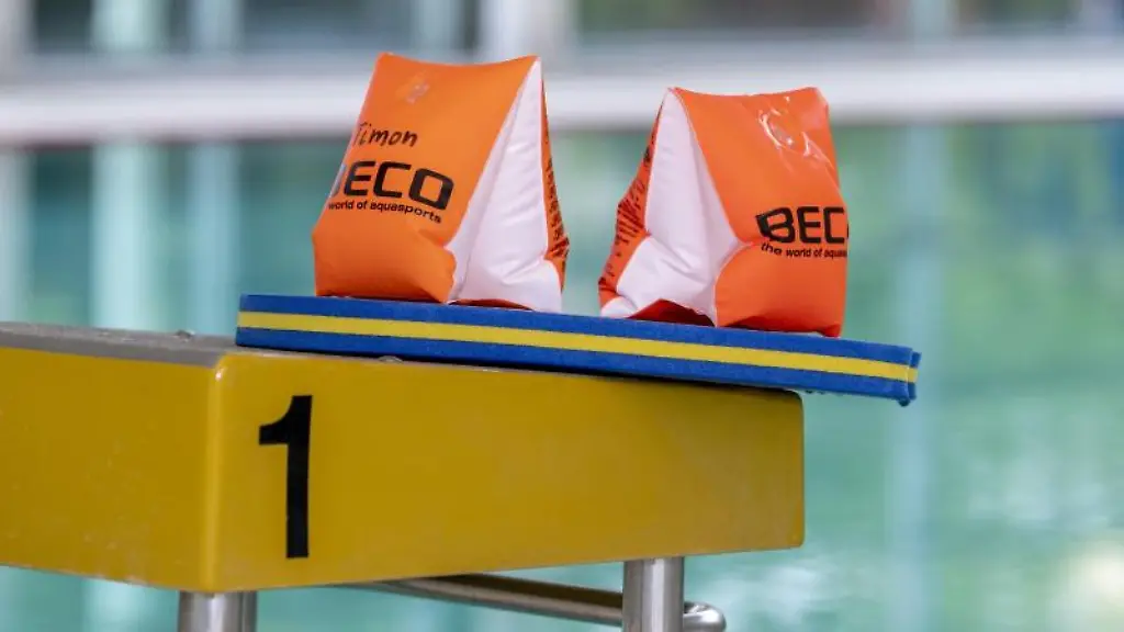 Zwei-Schwimmfluegel-und-ein-Schwimmbrett-liegen-auf-einem-Startblock