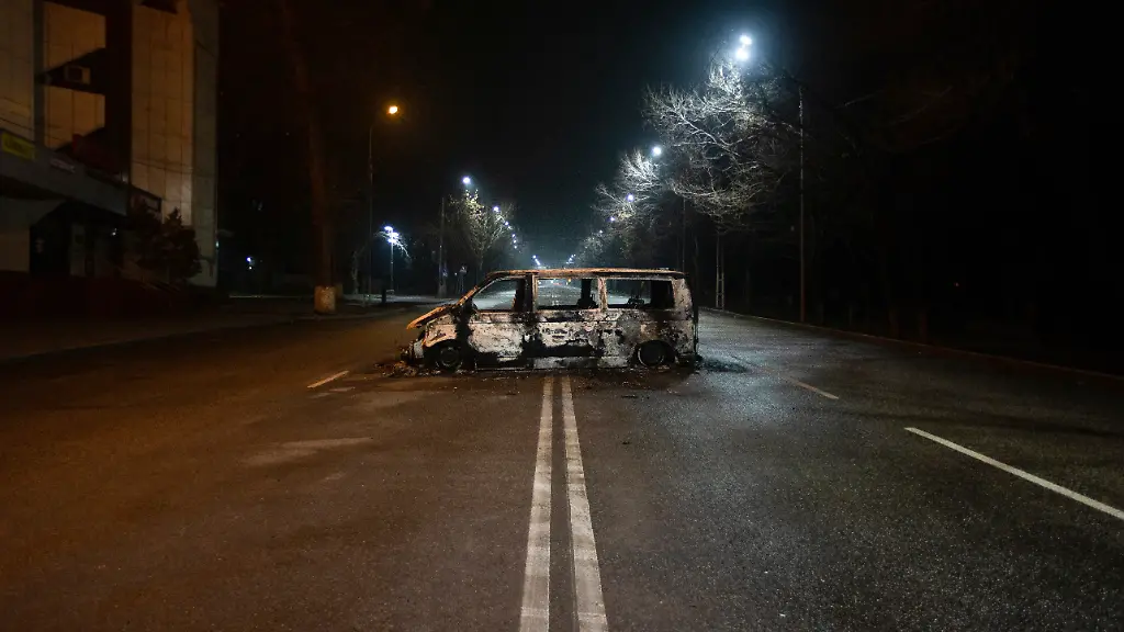 Ein-ausgebrannter-Polizeibus-steht-auf-einer-verlassenen-Strasse-in-der-kasachischen-Metropole-Almaty