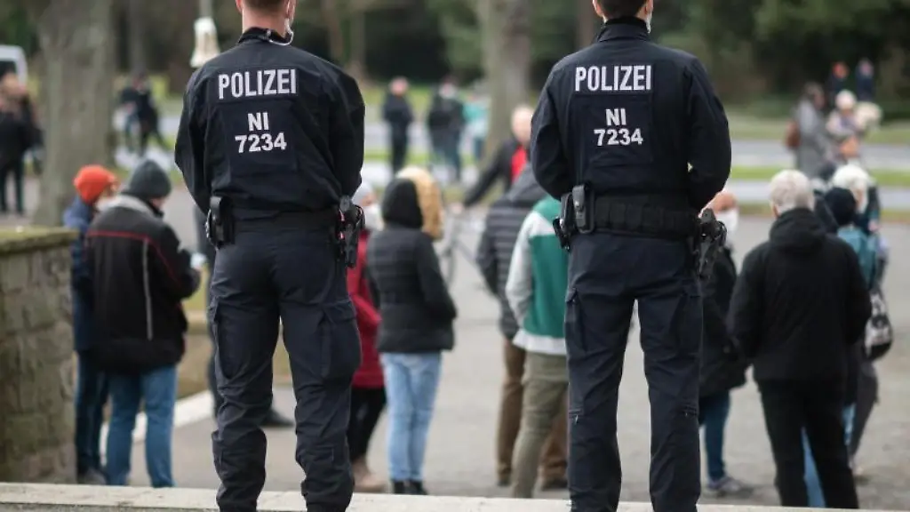Polizisten-stehen-waehrend-eines-Corona-Spaziergangs-vor-einer-Gruppe-von-Teilnehmern