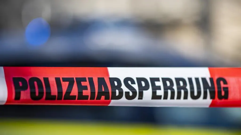 Ein-Absperrband-mit-der-Aufschrift-Polizeiabsperrung-ist-vor-einem-Polizeiwagen-aufgespannt