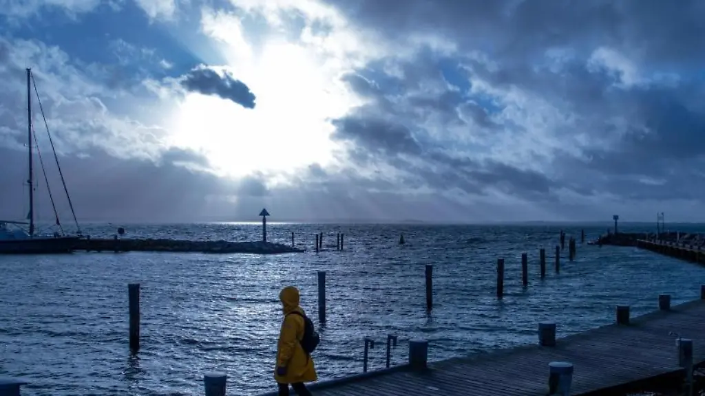Eine-Frau-mit-einer-gelben-Regenjacke-geht-ueber-den-Bootssteg