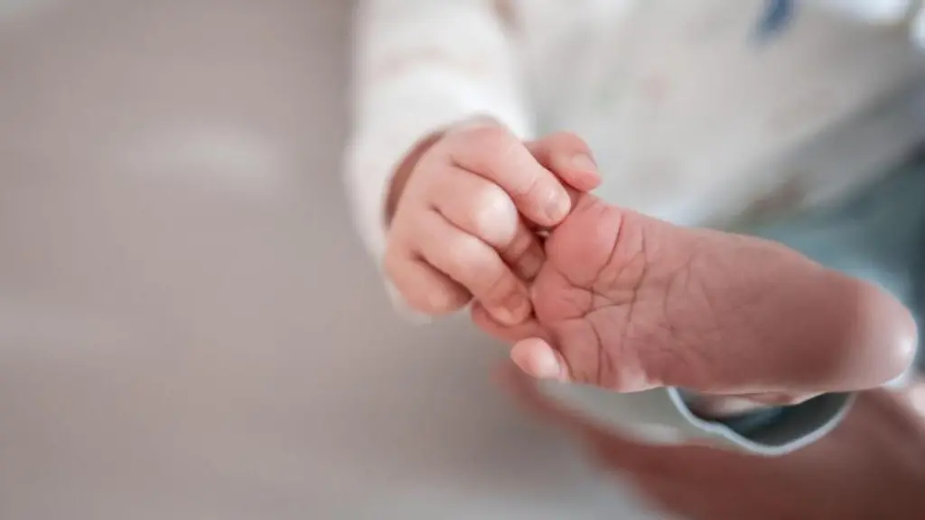 Ein-Baby-greift-mit-den-Fingern-nach-seinem-Fuss