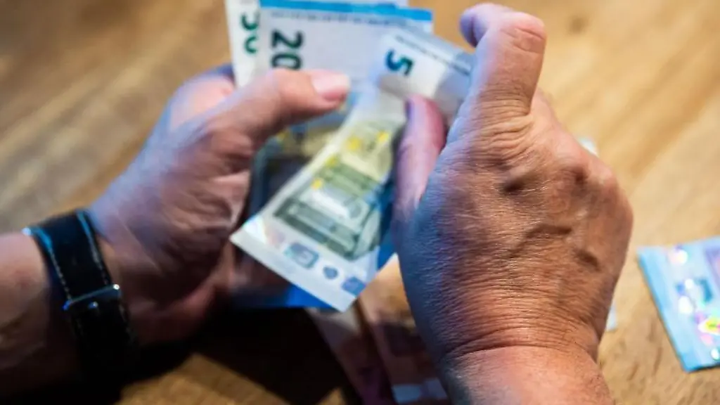 Ein-Mann-sitzt-an-einem-Tisch-und-zaehlt-Geld