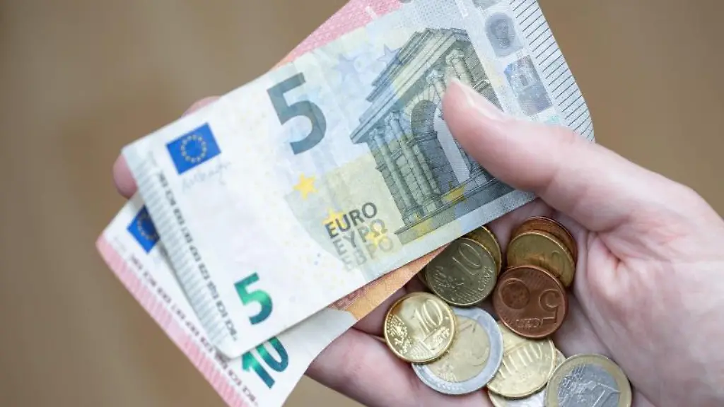 Eine-Frau-haelt-Geldscheine-und-Muenzen-in-der-Hand