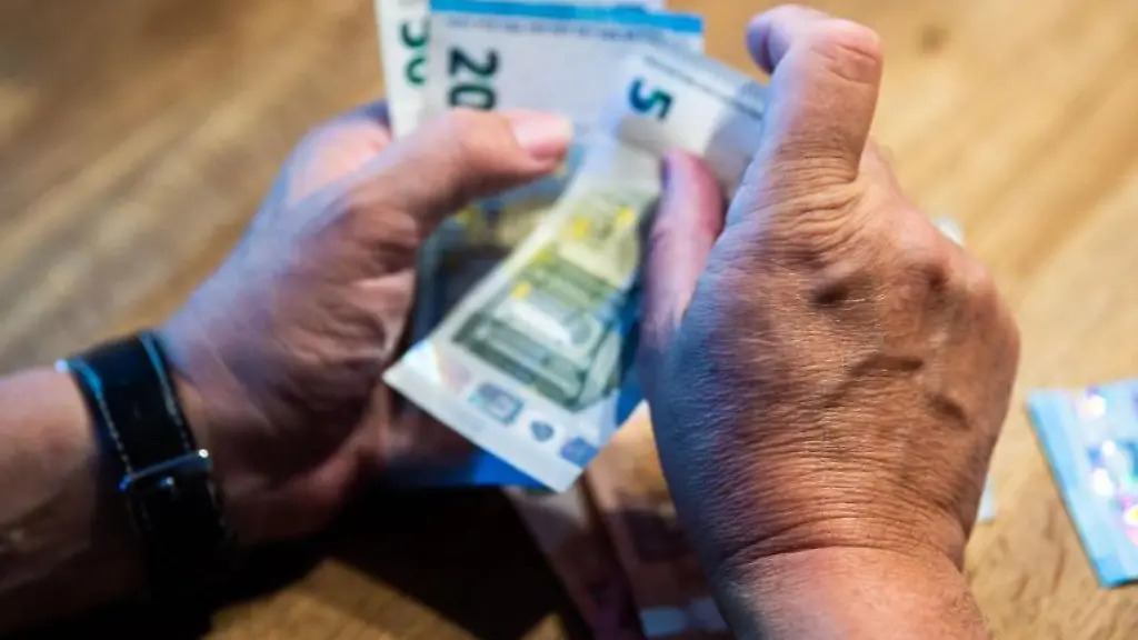 Ein-Mann-sitzt-am-Tisch-und-zaehlt-Geld