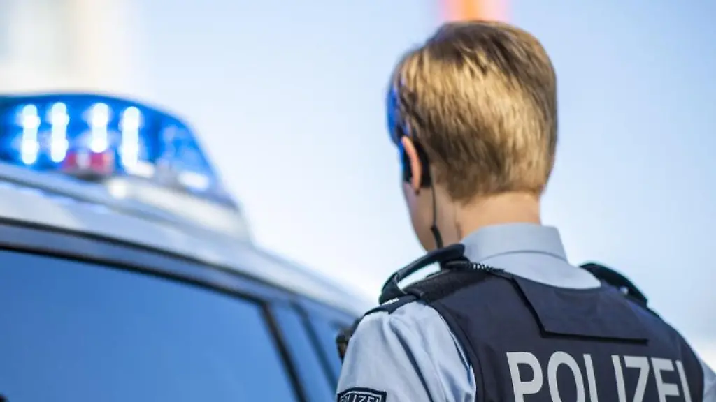 Eine-Polizistin-steht-vor-einem-Streifenwagen