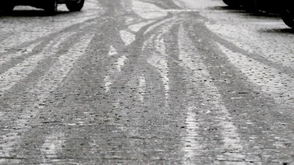 Fahrspuren-zeichnen-sich-im-Eis-auf-einer-Fahrbahn-ab