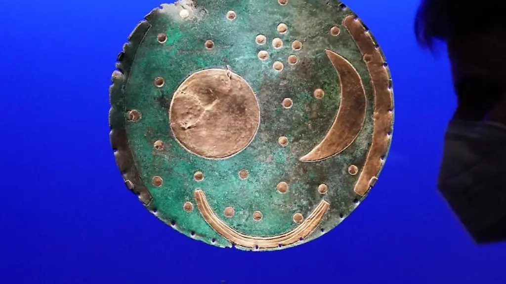 Ein-Besucher-betrachtet-die-Himmelsscheibe-oben-von-Nebra-mit-dem-gesamten-Fundstand