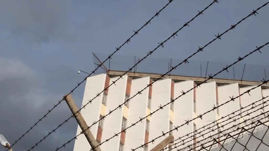 Ein-Stacheldrahtzaun-umzaeunt-das-Gelaende-einer-Justizvollzugsanstalt