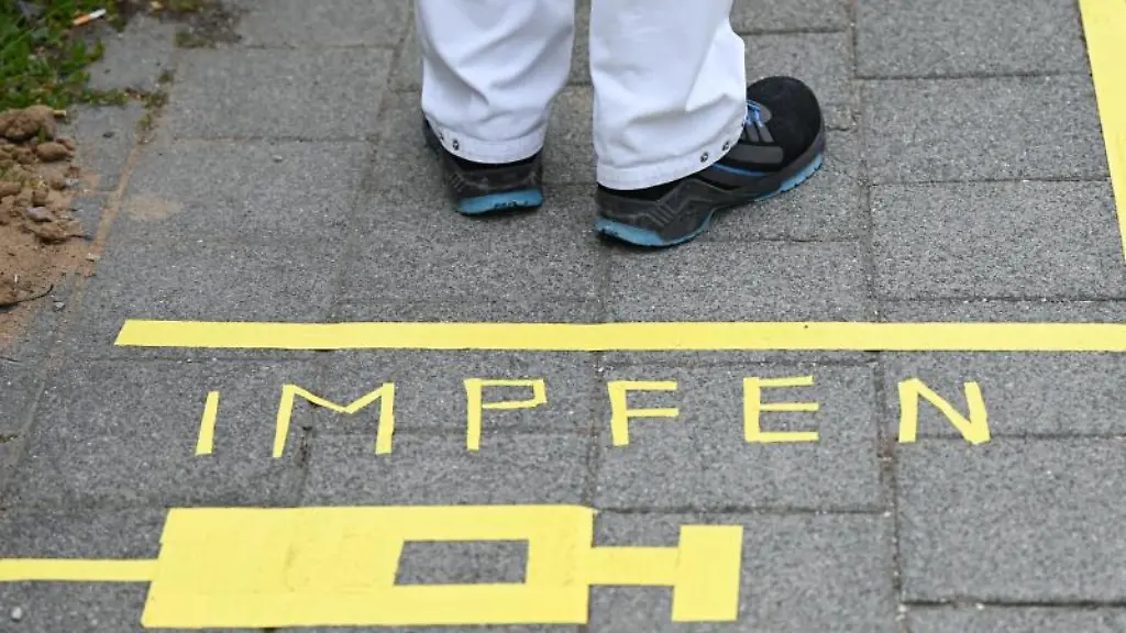 Ein-Mann-steht-an-einem-Covid-19-Impfcenter-hinter-der-Bodenaufschrift-Impfen