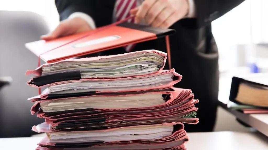 Ein-Staatsanwalt-steht-vor-einem-Stapel-Gerichtsakten