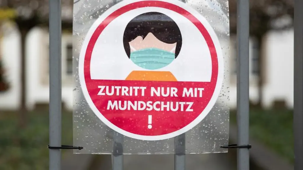 Ein-Schild-an-einem-Eingang-weist-auf-das-Tragen-einer-Maske-hin