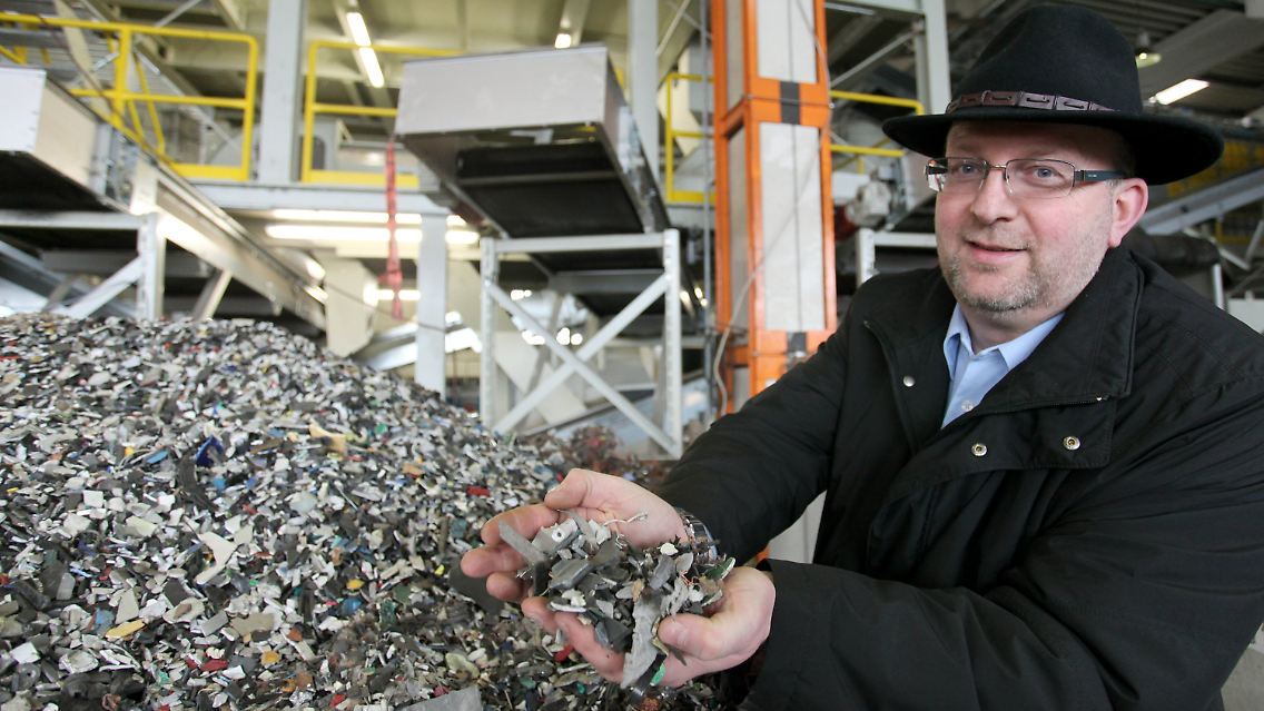 Adamec hält zerkleinerten Elektronikschrott in den Händen, der anschließend in alle einzelnen Rohstoffe getrennt wird.