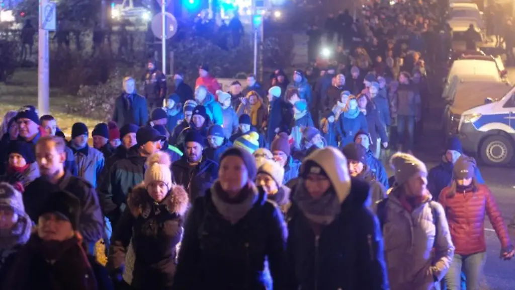 Kritiker-der-Coronamassnahmen-gehen-eine-Strasse-entlang