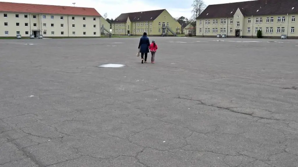 Eine-Frau-mit-Kind-geht-in-einer-Fluechtlingsunterkunft-im-Camp-Bad-Fallingbostel-ueber-einen-Platz
