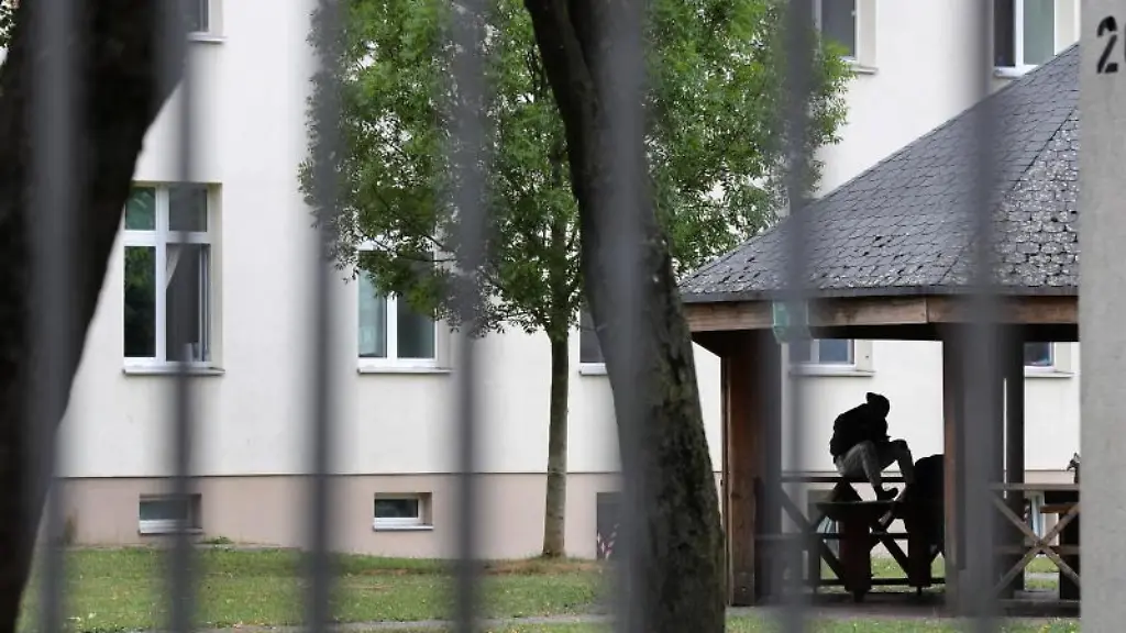 Ein-Asylsuchender-sitzt-vor-einem-Wohnblock-im-Ankerzentrum