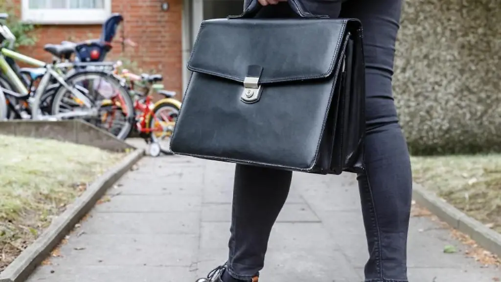 Eine-Obergerichtsvollzieherin-geht-mit-ihrer-Aktentasche-zu-einer-Wohnung